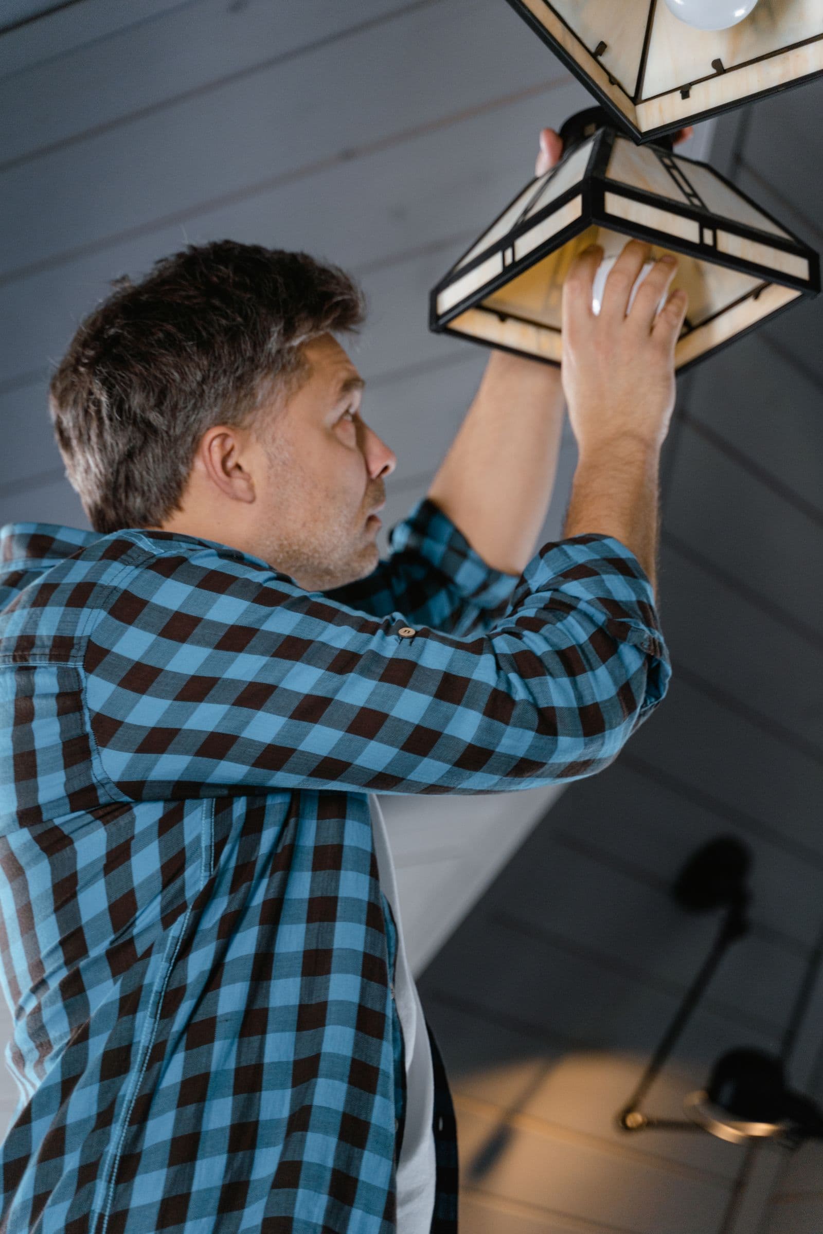 Handwerker montiert eine Deckenlampe in einer Wohnung